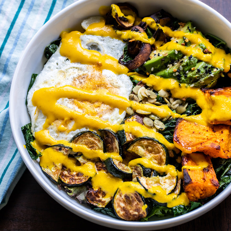 Buddha Bowl, roasted veggies and fried egg covered with Rooting For You dressing